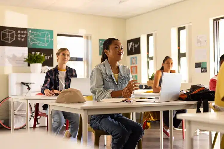 high-school-teenagers-using-laptops-listening-attentively-classroom